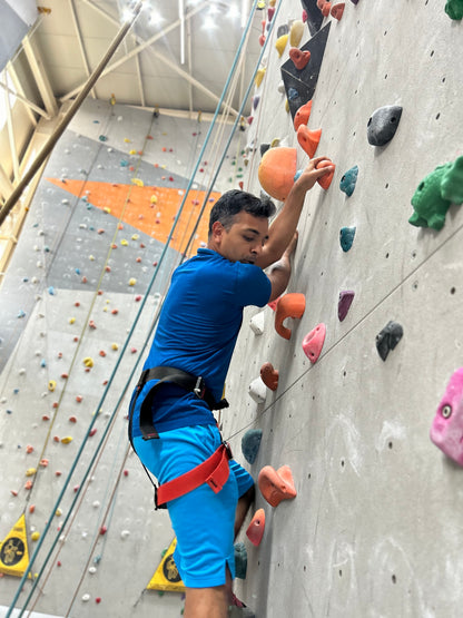 A man climbs a rock wall in an indoor climbing gym.