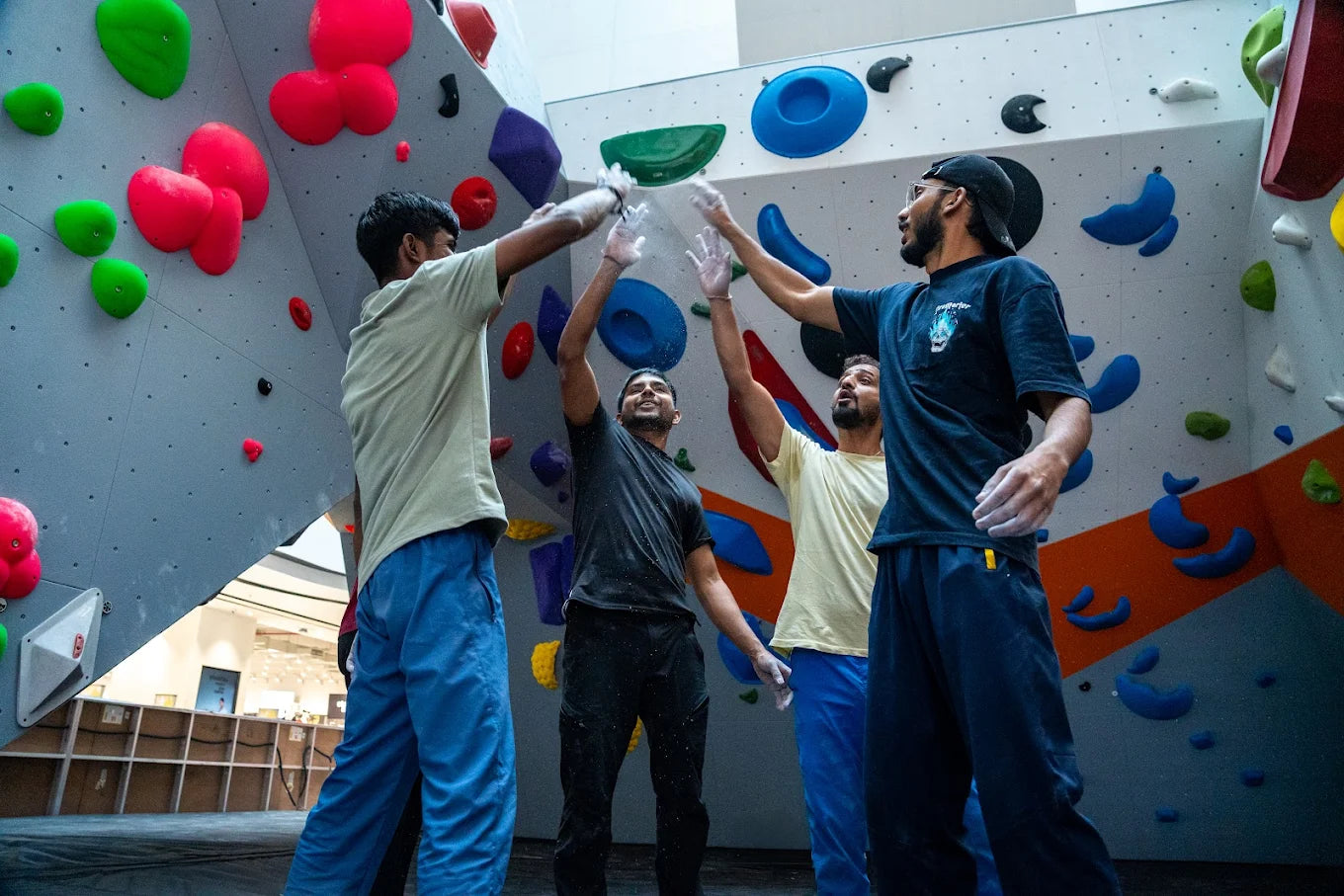 Four young men high-five on a climbing wall.
