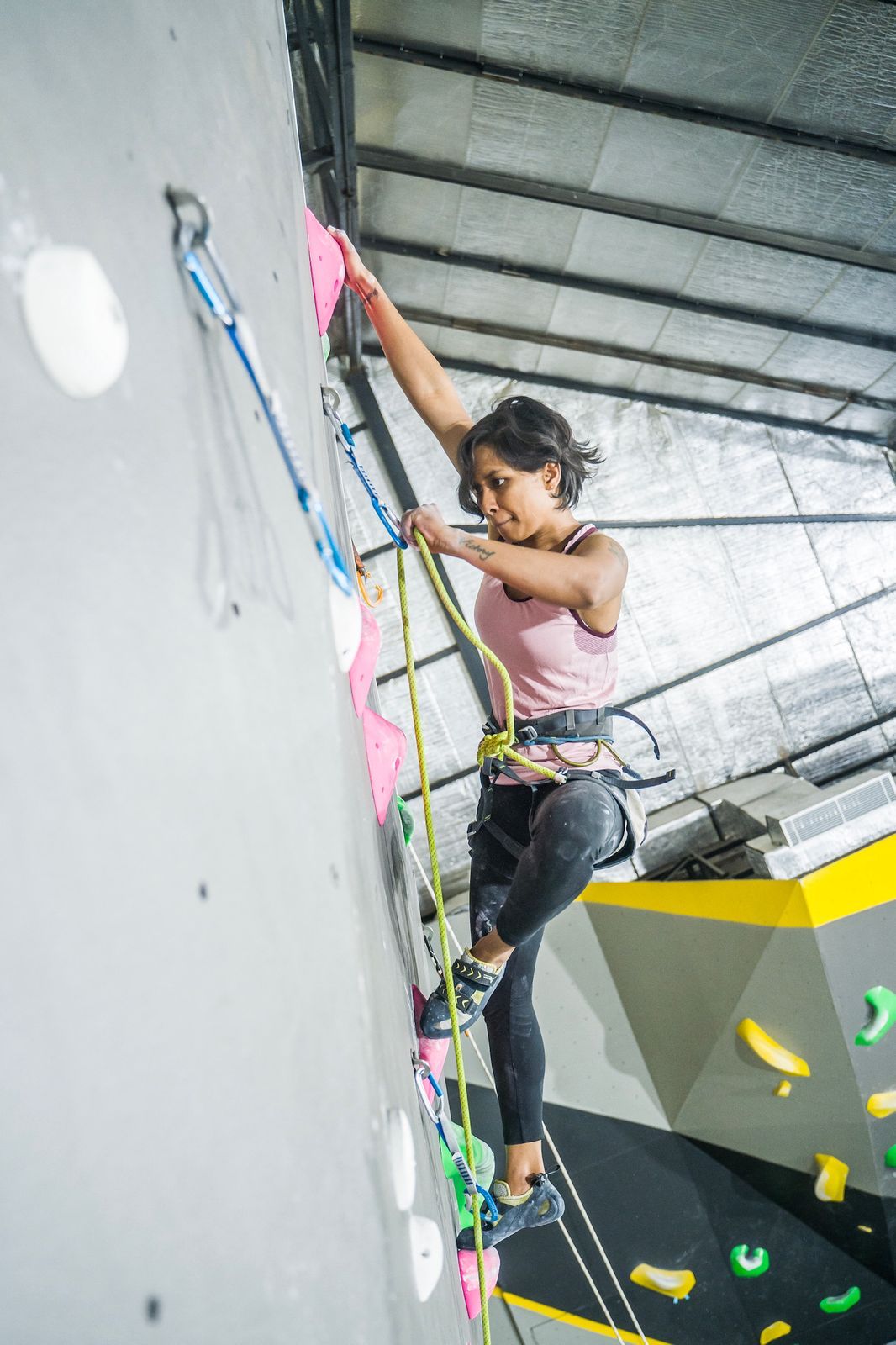 Person climbing on an indoor rock wall with colorful holds.