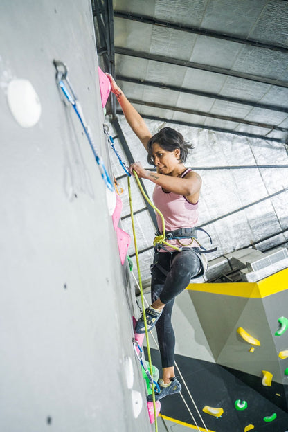 Person climbing on an indoor rock wall with colorful holds.