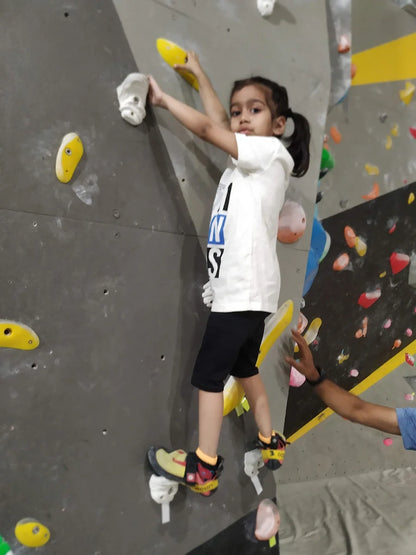 Child climbing on an indoor rock wall with colorful holds.