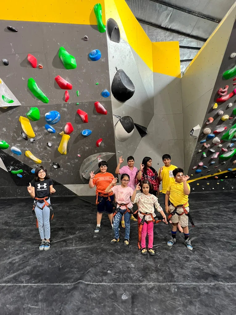 Group of children posing with climbing harnesses in front of colorful indoor climbing walls at Sector 132 Noida