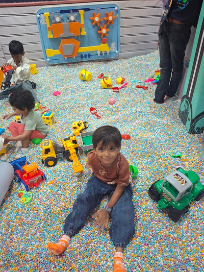 Young children play with toys in a ball pit filled with colorful balls.