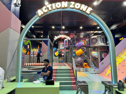 An indoor adventure park with trampolines, slides, and climbing walls, featuring young people playing.