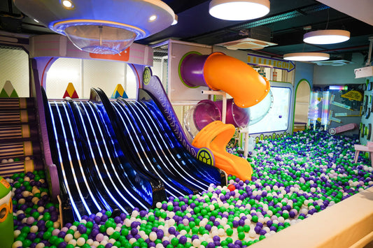 Indoor play area with glowing black slides and orange tube slide over colorful ball pit at Rumble Zone Sector 57 Gurugram