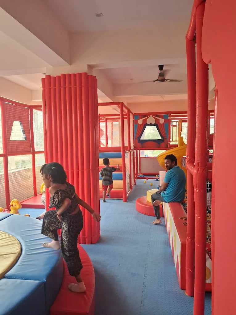 Children play in a colorful indoor playground while a man watches.
