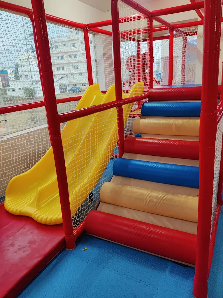 A colorful indoor playground with a yellow slide and padded steps for children.