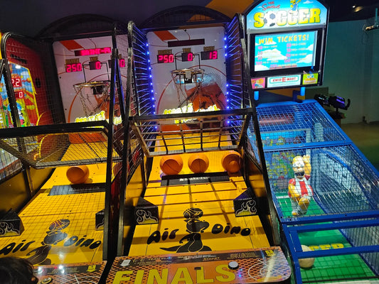 Arcade game area with basketball and soccer games, featuring a Homer Simpson figure.