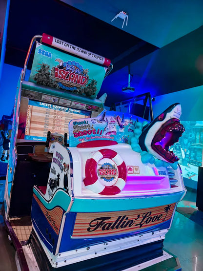 An arcade game shaped like a boat with a shark, featuring a tropical island theme.