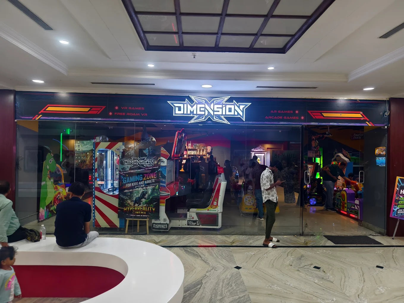 A gaming zone with arcade machines and people playing.