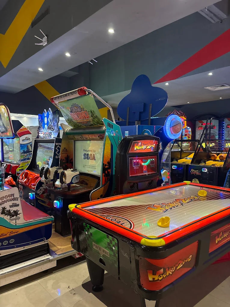 An arcade with various games, including an air hockey table and racing games.