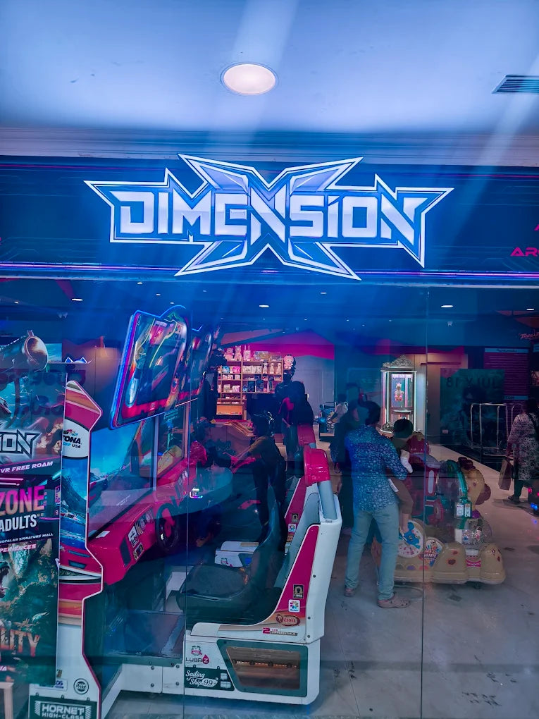 Arcade with racing game machines and people playing.