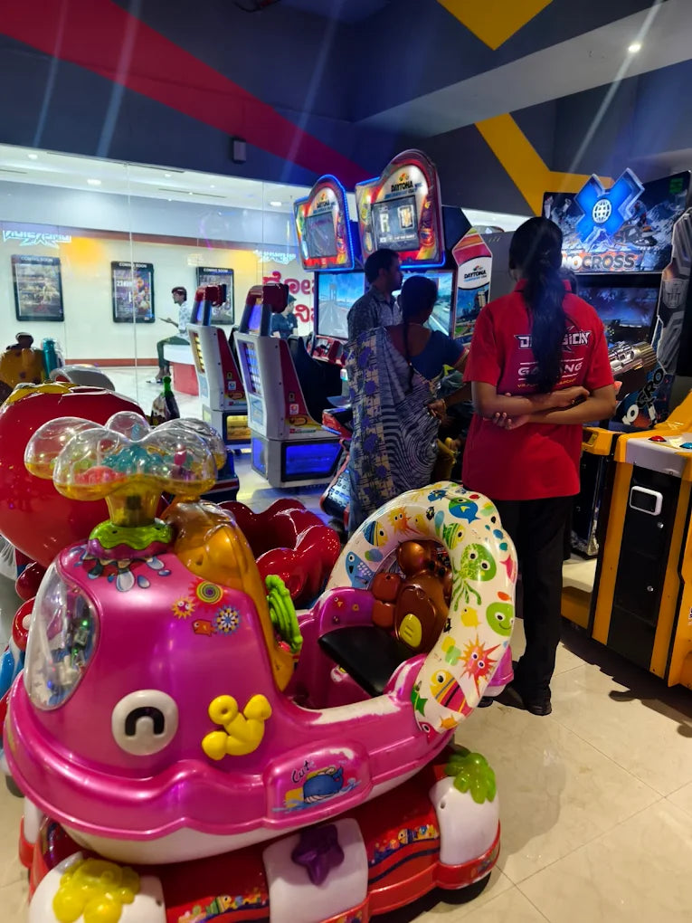 Children's amusement ride in an arcade with people playing video games.