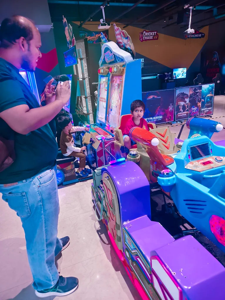 A man photographs children playing on colorful VR arcade rides.