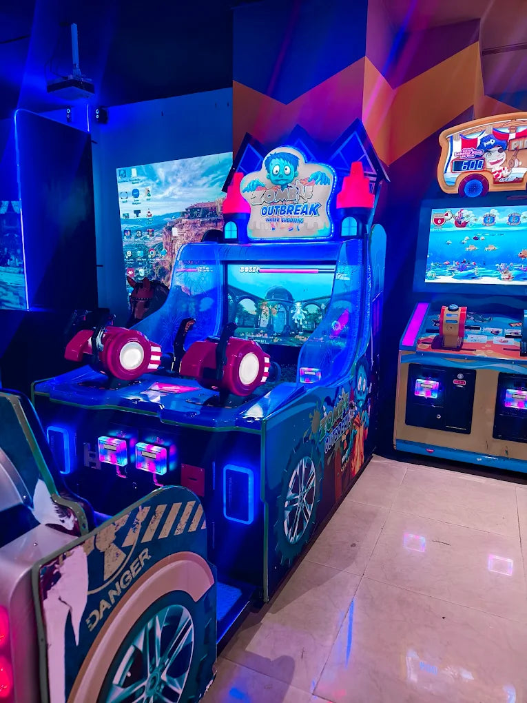 Arcade game machines with bright lights and colorful graphics, including a "Zombie Outbreak" game.