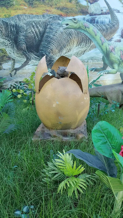 A dinosaur baby hatches from a large egg in a grassy area with dinosaur murals in the background.