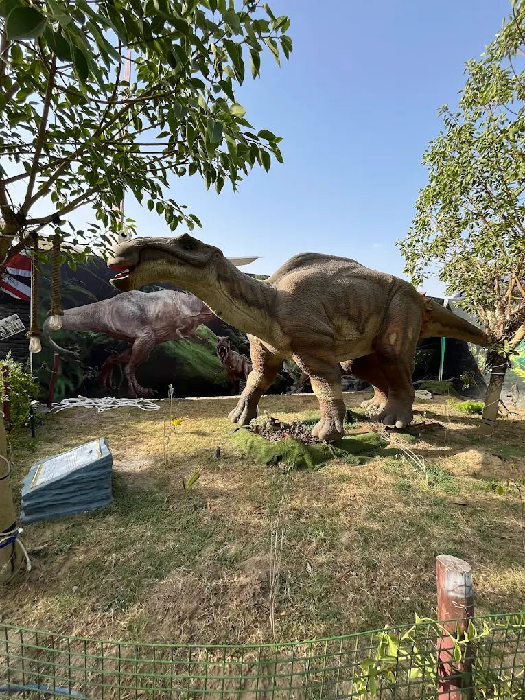 A dinosaur exhibit with realistic models of dinosaurs in a park setting.
