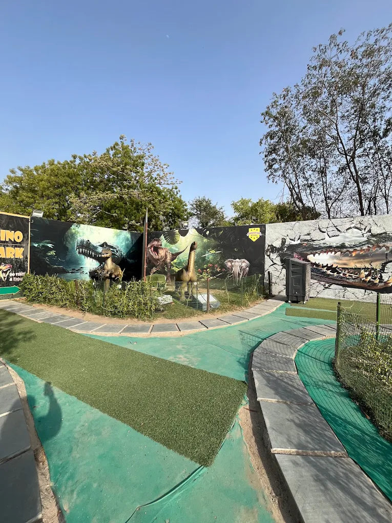 A dinosaur-themed park with artificial grass pathways and dinosaur models.