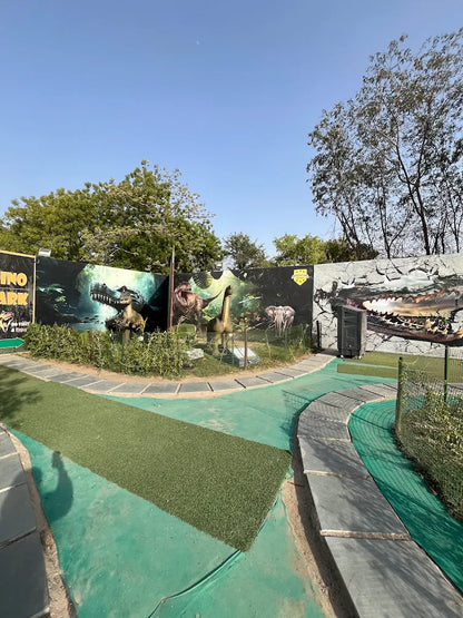 A dinosaur-themed park with artificial grass pathways and dinosaur models.