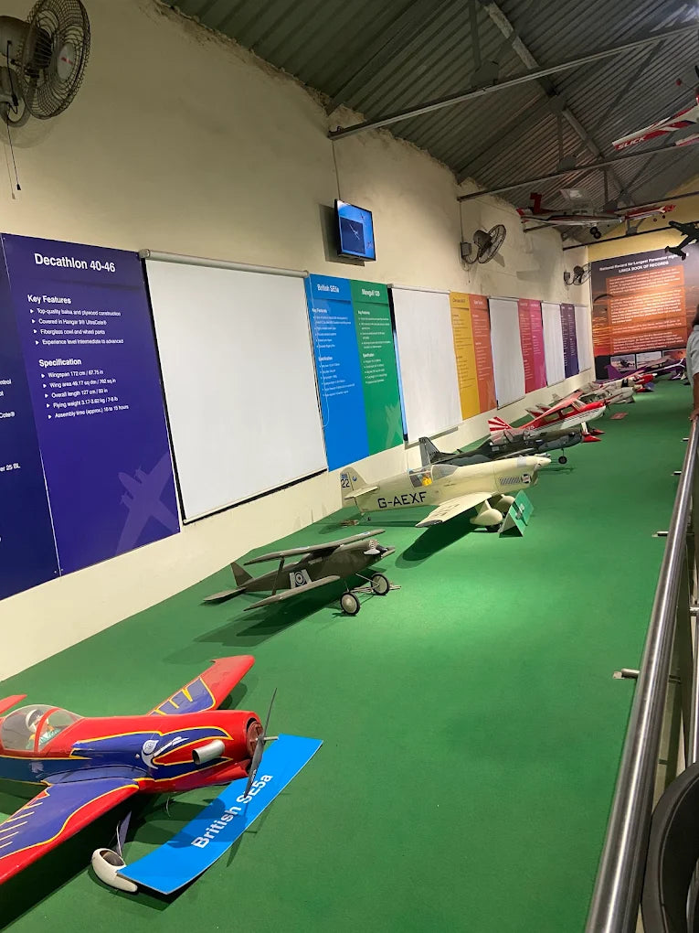 Model airplanes are displayed on a green surface in a museum.