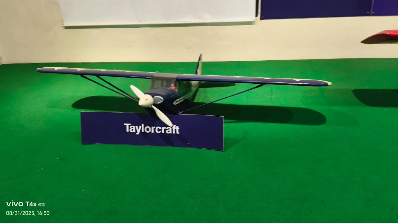 A model airplane labeled "Taylorcraft" sits on a green surface.
