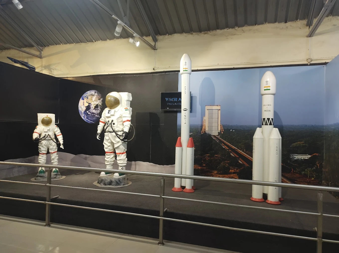 Models of astronauts and rockets are displayed in a museum exhibit.