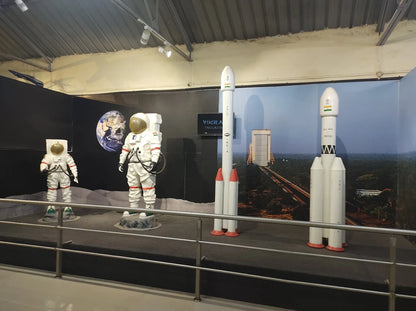 Models of astronauts and rockets are displayed in a museum exhibit.