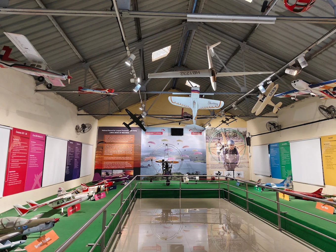 Model airplanes hang from the ceiling in a museum exhibit about paramotoring.