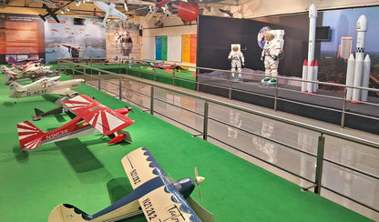 Models of airplanes and rockets are displayed in a museum exhibit with astronauts.