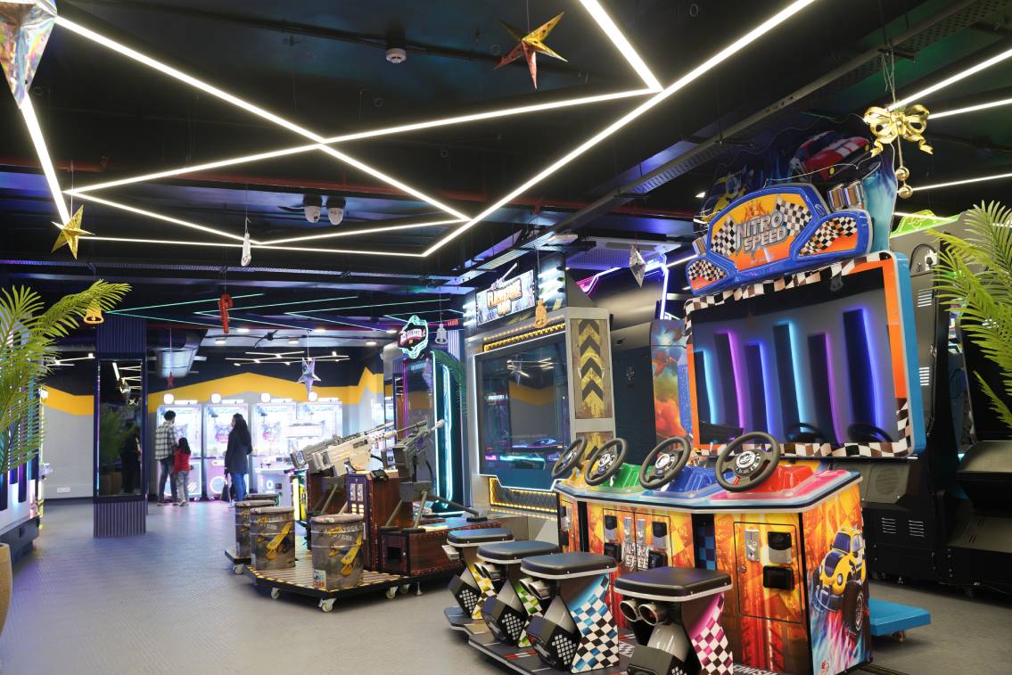 An arcade with racing games and people playing.