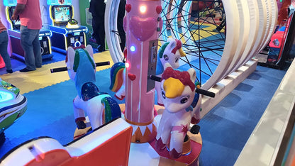 Children's carousel with unicorn rides and arcade games in an indoor amusement area.