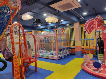 A colorful indoor playground with soft play structures and a ball pit, featuring children playing.