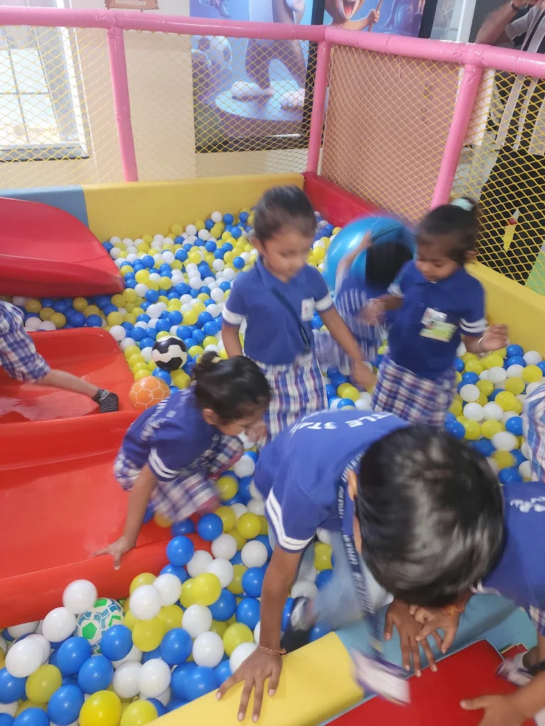 Young children play in a ball pit with colorful balls and slides.