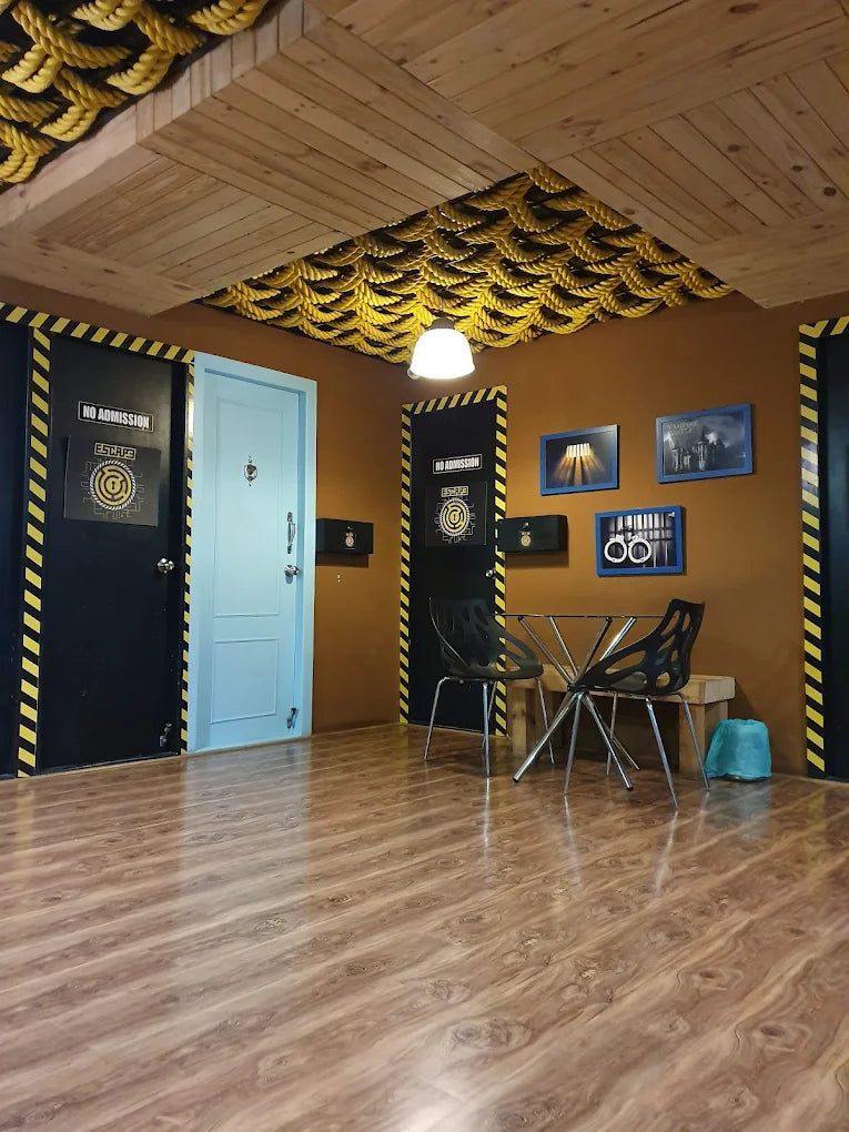 An escape room entrance with a light blue door, black doors with yellow stripes, and a table with chairs.