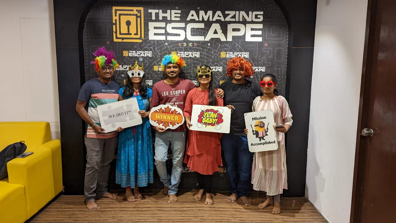 A group of young adults in colorful wigs and props pose for a photo after completing an escape room challenge.