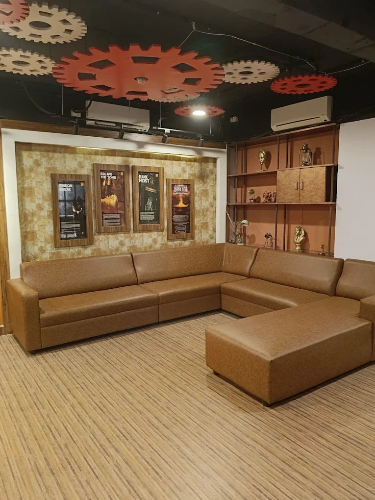 A brown sectional sofa and ottoman in a room with gear decorations on the ceiling.