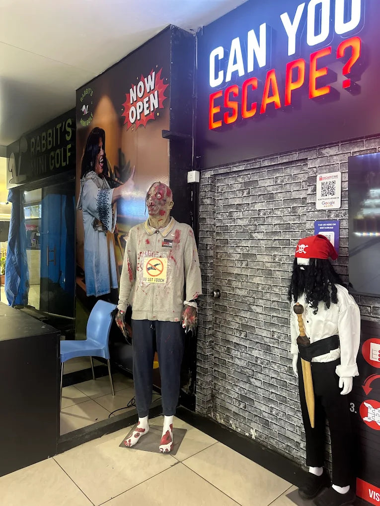 Mannequins dressed as a zombie and a pirate stand outside an escape room with "CAN YOU ESCAPE?" signage.