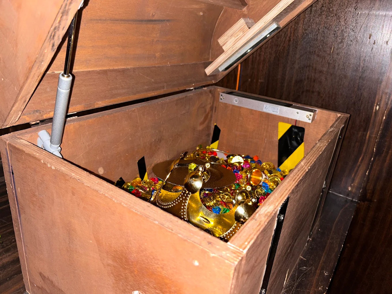 A wooden chest overflowing with colorful plastic jewels and gold coins.