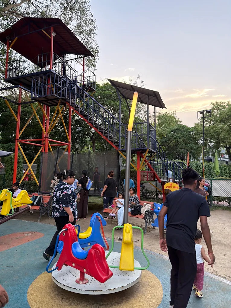 Children and adults enjoy a playground with a zipline and merry-go-round.