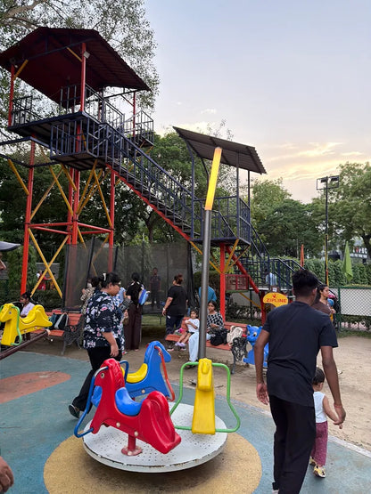 Children and adults enjoy a playground with a zipline and merry-go-round.