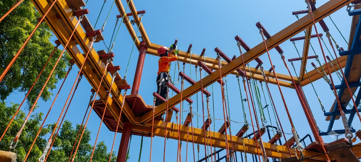 A child in a helmet and safety harness navigates an aerial adventure course.