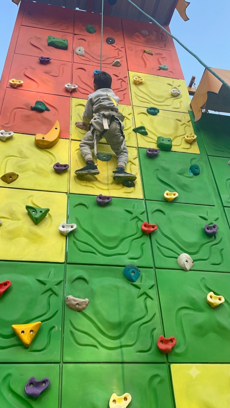 A child in a harness climbs a colorful indoor rock wall.