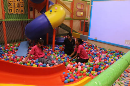 Children enjoying a colorful ball pit with slides and climbing structures in a lively indoor play area
