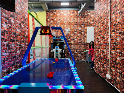 Indoor game room featuring an illuminated air hockey table set against brick-patterned walls and dark flooring