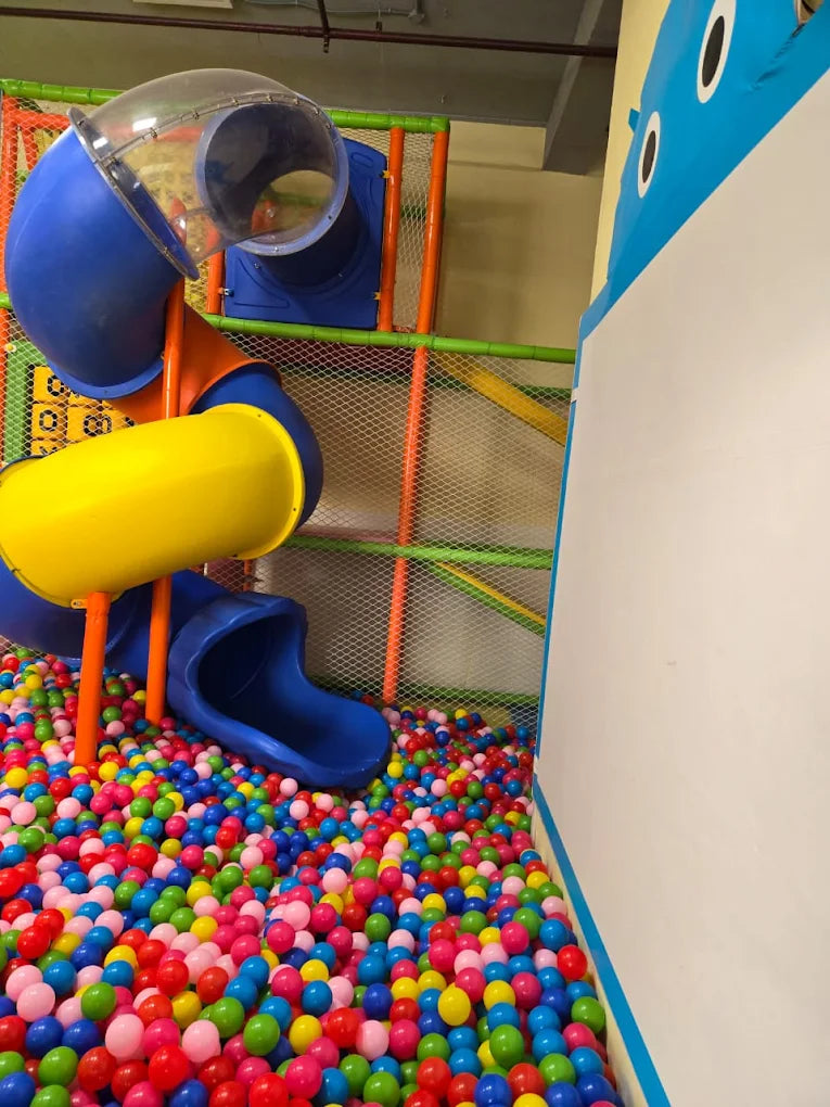 Colorful spiral slide ending in a vibrant ball pit filled with multi-colored plastic balls in an indoor play area