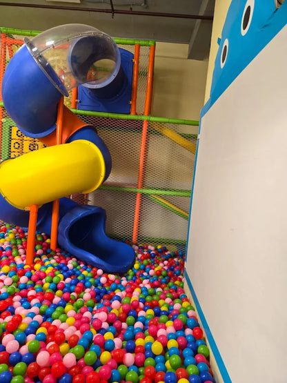 Colorful spiral slide ending in a vibrant ball pit filled with multi-colored plastic balls in an indoor play area