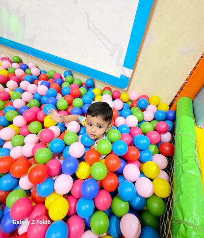 Toddler playing and surrounded by colorful plastic balls in a safe and fun indoor kids play area