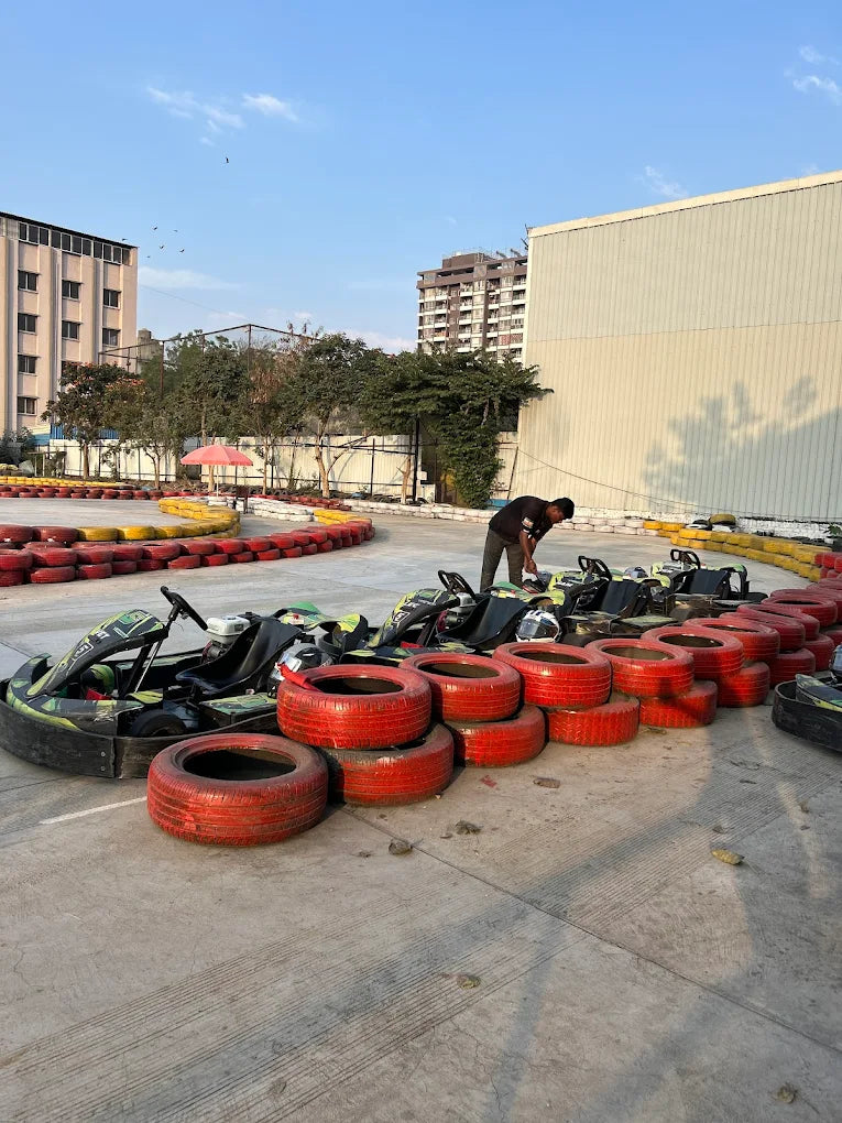 Go-karts are lined up on a track with a person in the background. Red and yellow tires form the track's barrier.