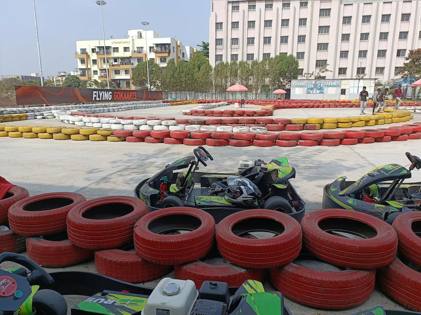 Go-karts are parked at a track with tire barriers and a building in the background.