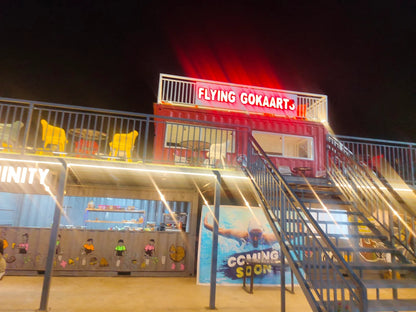 A brightly lit outdoor venue with a "Flying Gokaarts" sign, stairs, and a "Coming Soon" poster.